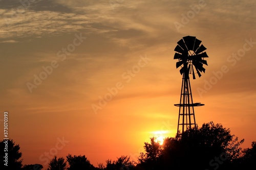 Kansas colorful Sunset with clouds and a Windmill silhouette out in the country north of Hutchinson Kansas USA.