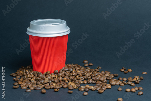 Red coffee cup with scattered coffee beans on dark background photo