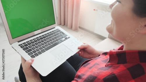 A girl sits on the couch at home and holds a laptop, communicates online.