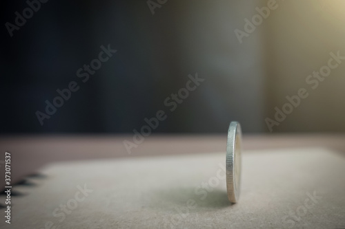 coins always have 2 side idiom idea concept, a Thai coin rolling on table with blurred background sunshine strong ligthing