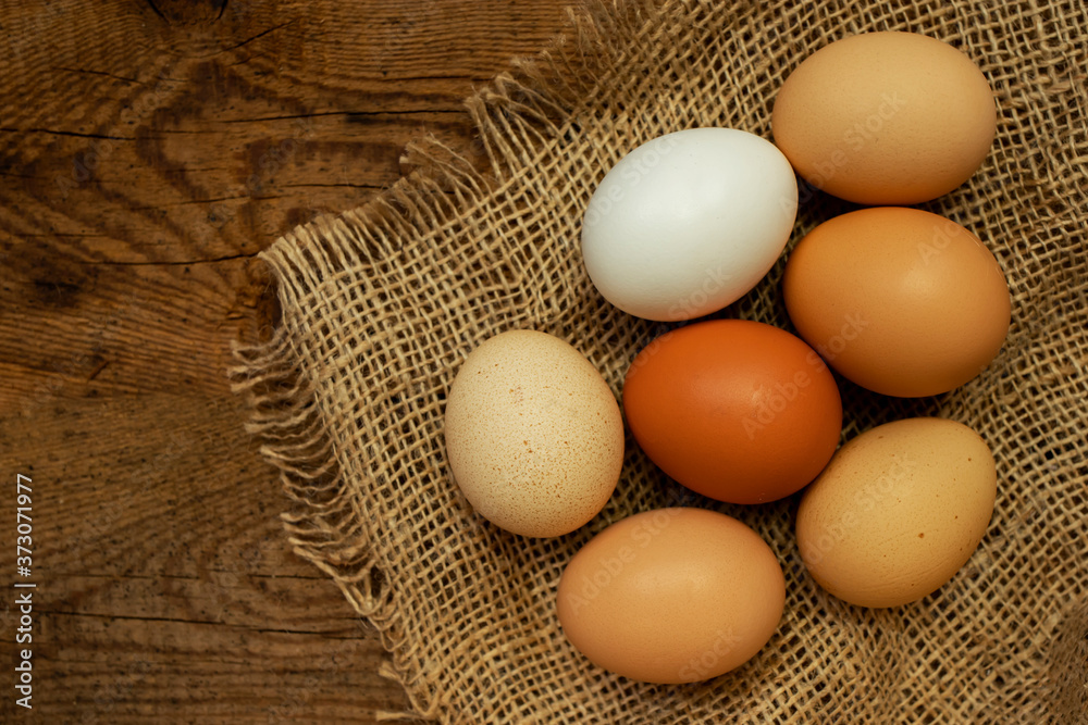 Fresh colorful chicken eggs on a natural wooden background and mat. Food background, top view. Place for text. Fresh colorful chicken eggs on a natural wooden background and mat. Food background, top view. Place for text.