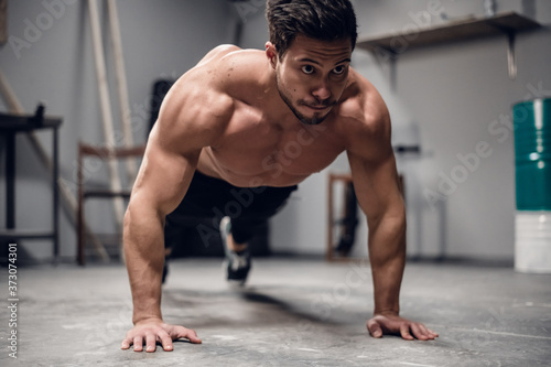 a muscular sportsman does push-UPS from the floor in the gym.