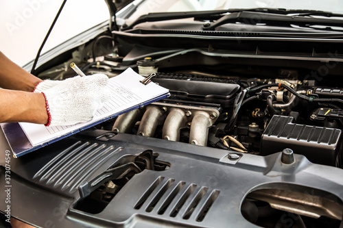 Auto mechanic using checklist for car engine systems after fixed. concepts of car insurance support and services.