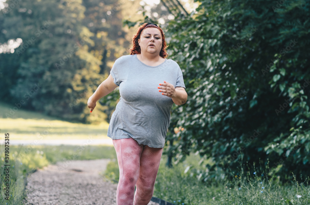 An obese woman running on a treadmill, weight loss training in nature on a sunny day An obese woman running on a treadmill, weight loss training in nature on a sunny day