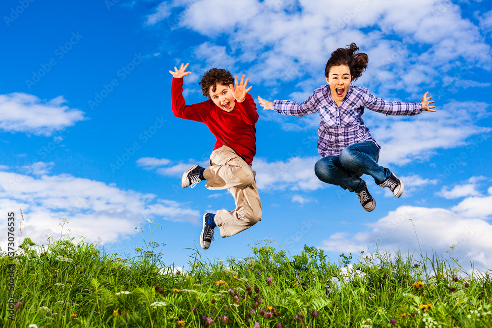Girl and boy running, jumping against blue sky
Girl and boy running, jumping against blue sky