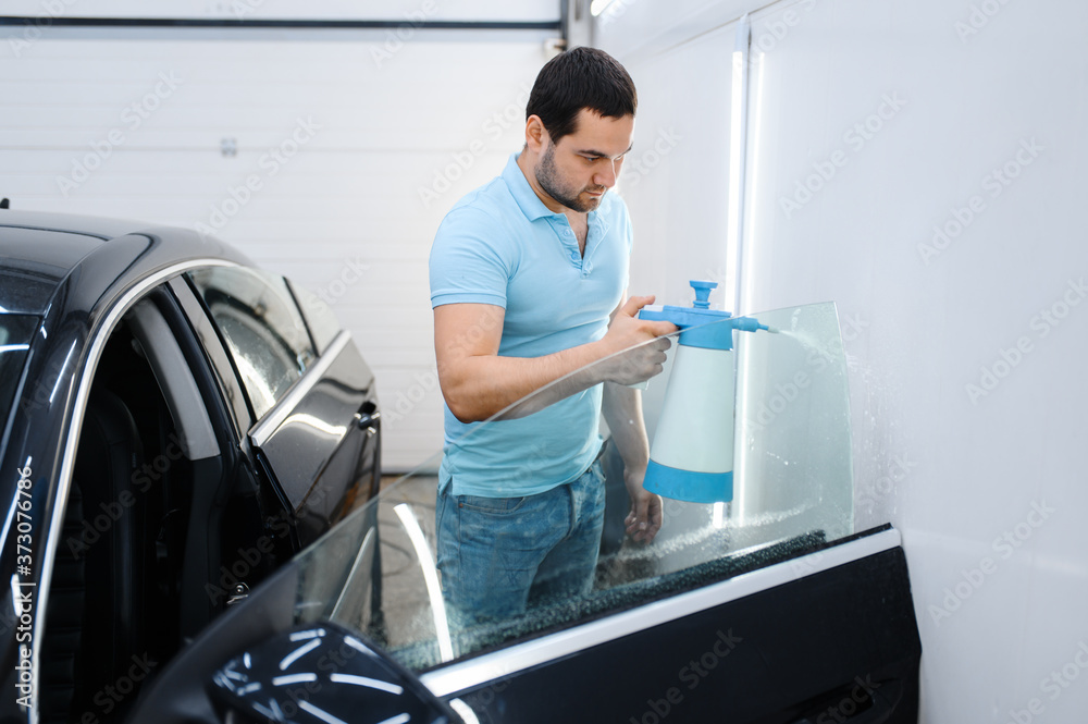 Male wrapper with spray prepares car for tinting Male wrapper with spray prepares car for tinting