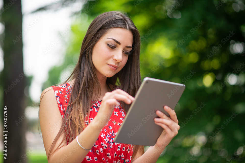 Woman using a digital tablet in the park Woman using a digital tablet in the park