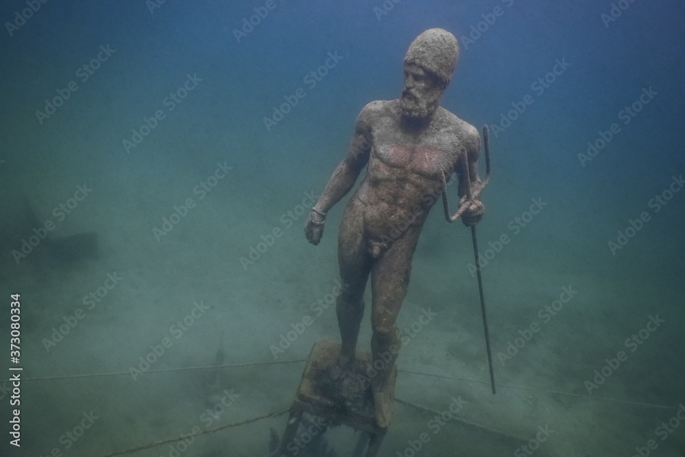 statue poseidon with a trident at the ground from a lake while diving