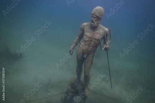 statue poseidon with a trident at the ground from a lake while diving