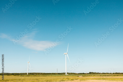 Windfarm generating clean renewable energy on sunny summer day with clear blue sky