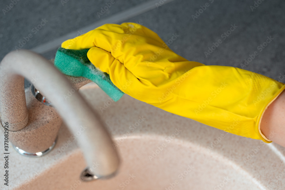 Hands in yellow gloves cleaning a sink with a sponge Hands in yellow gloves cleaning a sink with a sponge