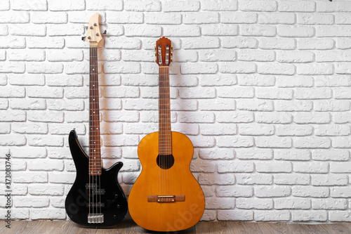 Set of guitars on the floor against white brick wall © fotofabrika