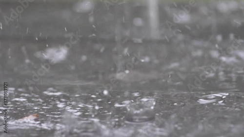 Slow motion speed close up scene on raindrop fall against and bounce on floor, flood from rainstrom in bad rainy day, natural pattern of pouring rain bumping on ground, grainy texture of water photo