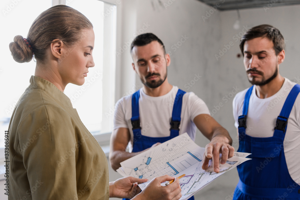Woman and two workers discussing the layout Woman and two workers discussing the layout