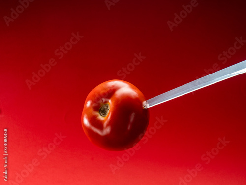 Tomato with knife on red background