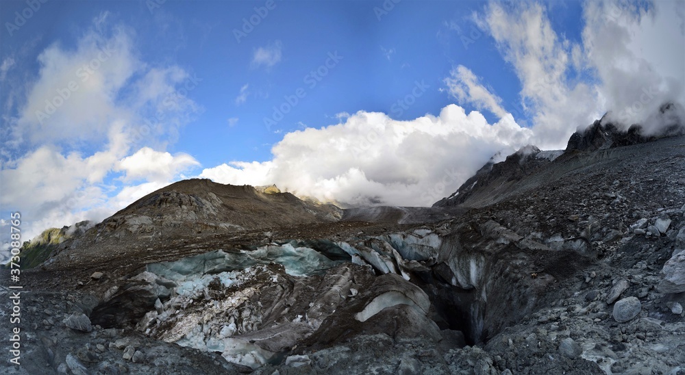 Glacier with blue ice in the Swiss Alps in Valais as a panorama with a bright blue sky