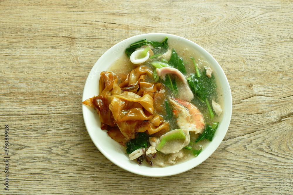 fried rice large noodles black soy sauce dressing mixed seafood and meat with Chinese kale in gravy sauce on plate fried rice large noodles black soy sauce dressing mixed seafood and meat with Chinese kale in gravy sauce on plate