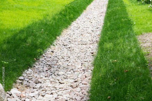 Drainage ditch filled with crushed granite with banks overgrown with lawn grass