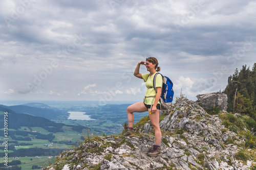 Adventure in the mountains. Young tourist girl on the top of a rocky mountain in Austria