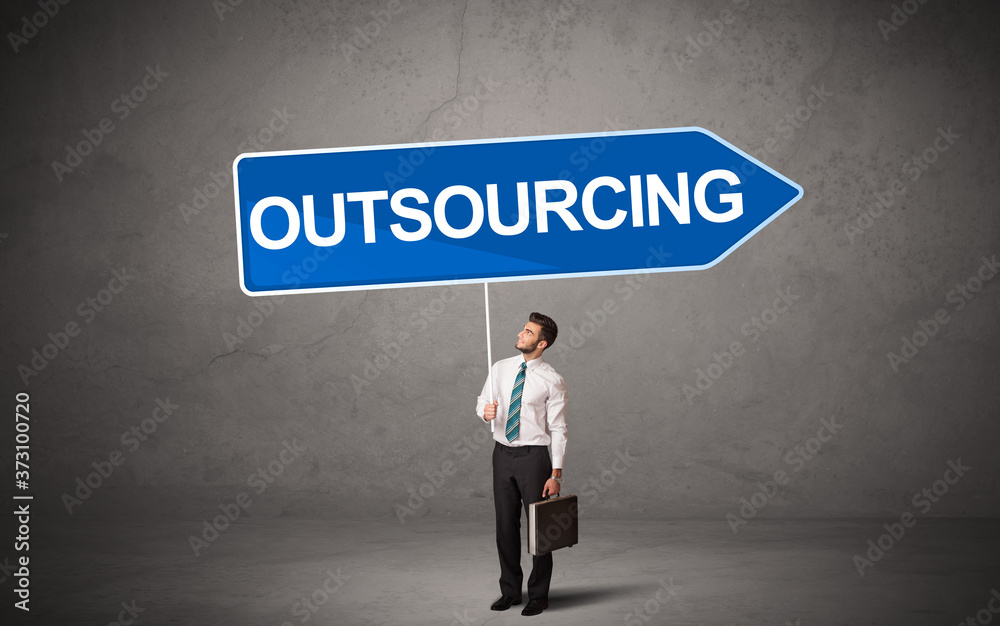 Young business person in casual holding road sign with OUTSOURCING inscription, new business direction concept Young business person in casual holding road sign with OUTSOURCING inscription, new business direction concept