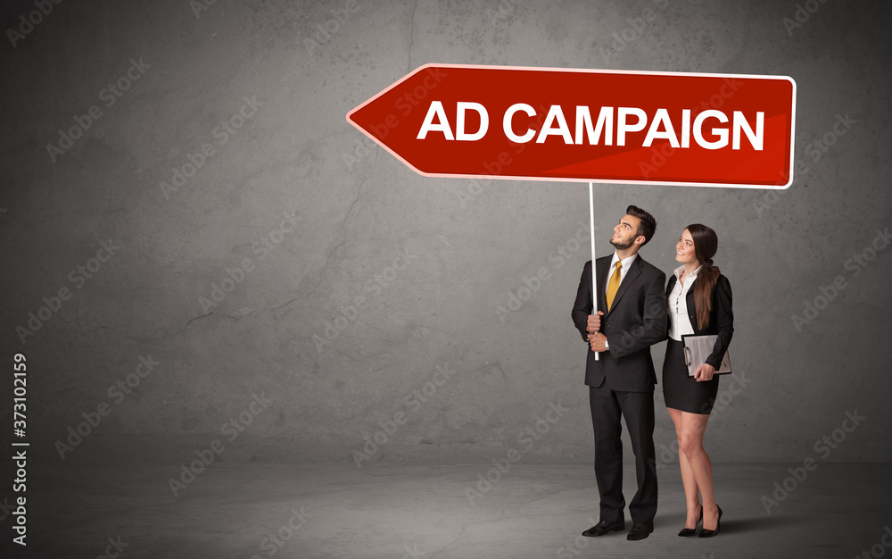 Young business person in casual holding road sign with AD CAMPAIGN inscription, new business direction concept Young business person in casual holding road sign with AD CAMPAIGN inscription, new business direction concept