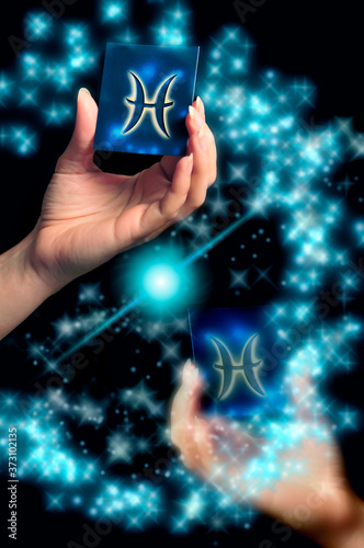 woman hand keeping a blue card with zodiac sign of  Pisces over black background with stars like astrology concept  © starblue