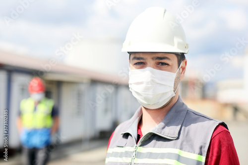 The worker is using a protective mask for coronavirus (covid-19) in the construction site.
