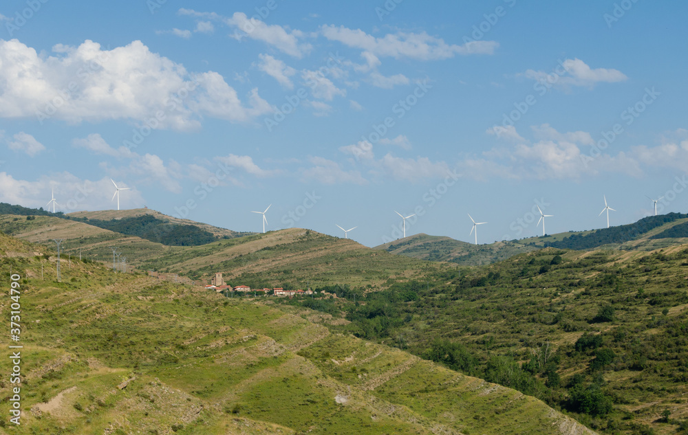 Village in the mountain with wind turbine or windmill providing renewable energy