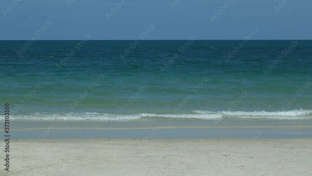 scene of soft wave from the sea on sandy tropical beach under the bright blue sky at summer day