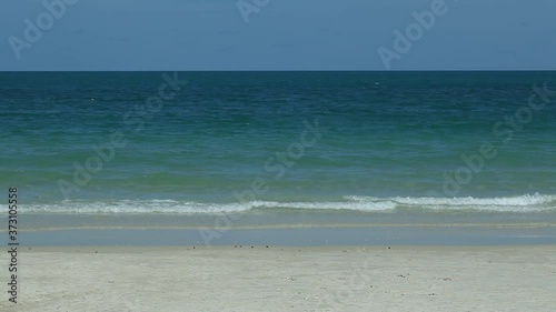 scene of soft wave from the sea on sandy tropical beach under the bright blue sky at summer day