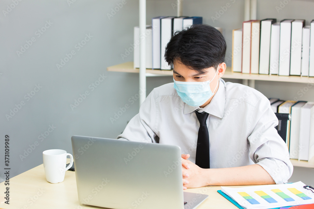 Male worker wearing a mask works with a laptop Male worker wearing a mask works with a laptop