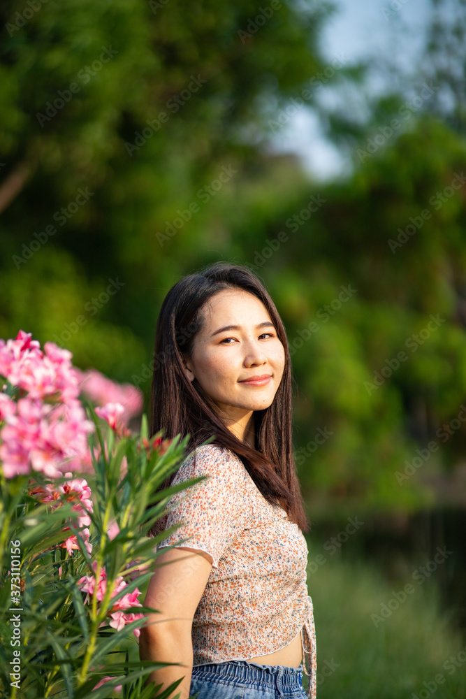 Beautiful Asian woman alone in the park with pink flowers Beautiful Asian woman alone in the park with pink flowers