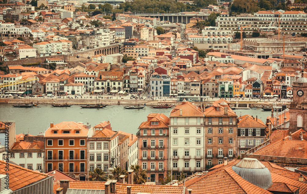 Suuny city with river behind the red tile roofs, view from top floor on historical Porto