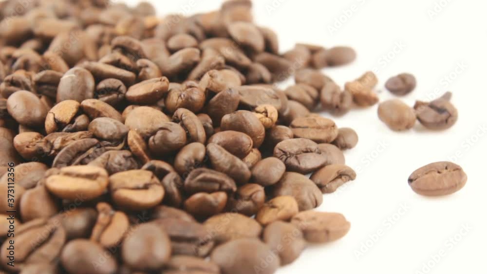Close-up of the rotation of coffee beans. Roasted grains of aromatic coffee rotate on a plate. Close-up of the rotation of coffee beans. Roasted grains of aromatic coffee rotate on a plate.