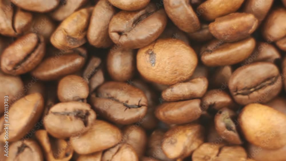 Close-up of the rotation of coffee beans. Roasted grains of aromatic coffee rotate on a plate. Close-up of the rotation of coffee beans. Roasted grains of aromatic coffee rotate on a plate.