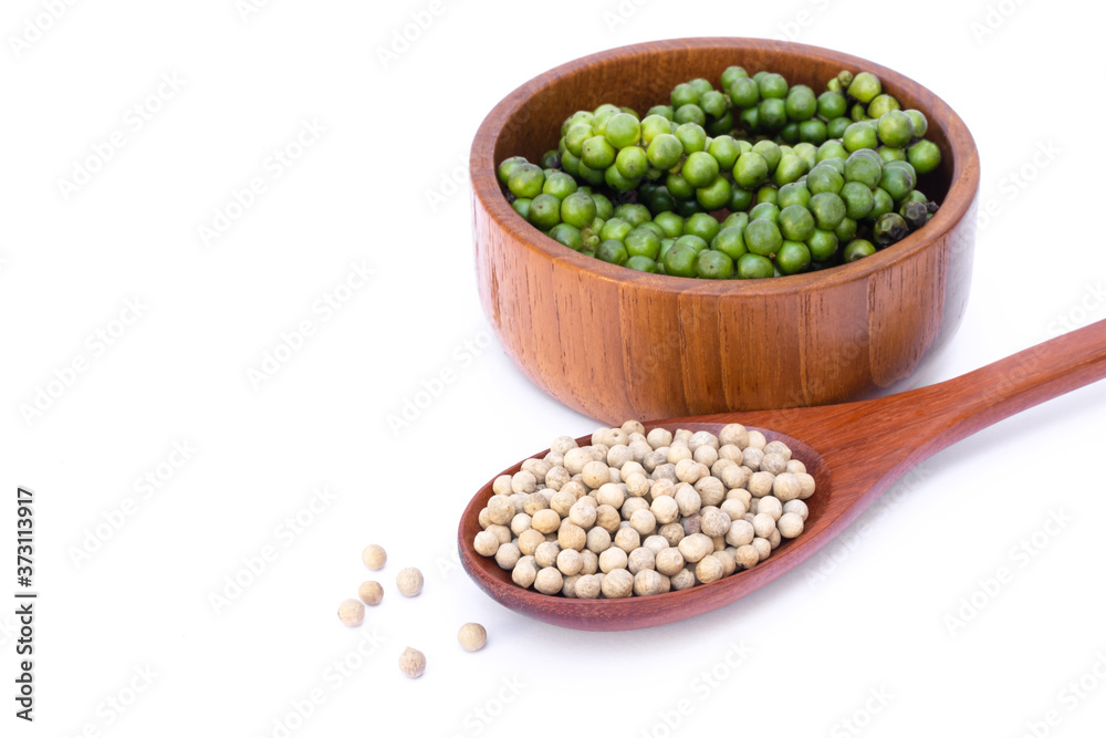 Closeup fresh green pepper in wooden bowl and white peppercorn seeds ( piper nigrum) in spoon isolated on white background. Closeup fresh green pepper in wooden bowl and white peppercorn seeds ( piper nigrum) in spoon isolated on white background.