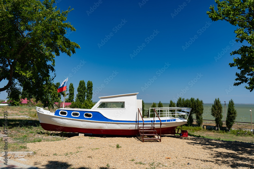 old broken boat on beach painted in colors of Russian flag witha pennant.
