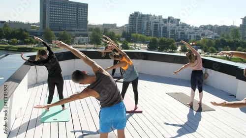 Group yoga or fitness classes. Training on the roof of the house. Outdoor sports. Many people do yoga exercises. Meditation and wellness lifestyle concept