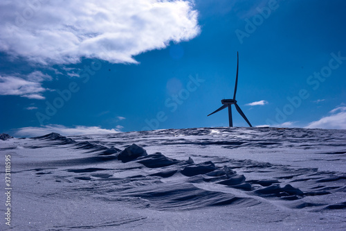 Wind generator background blue sky,at mountain covered with snow.