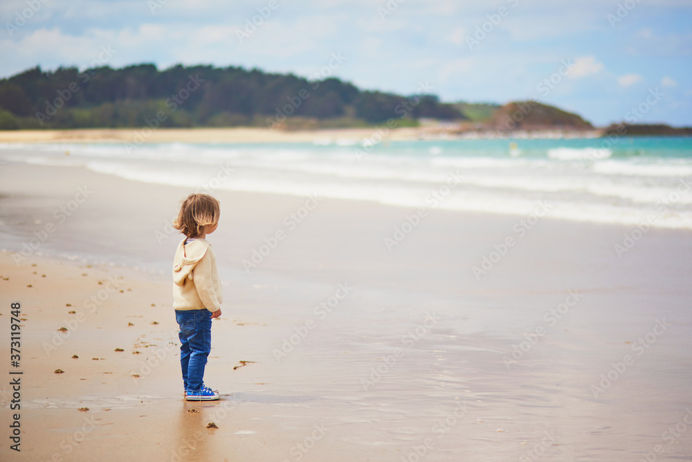 Adorable toddler girl on the sand beach at Atlantic coast of Brittany, France