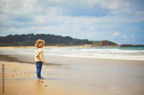 Adorable toddler girl on the sand beach at Atlantic coast of Brittany, France
