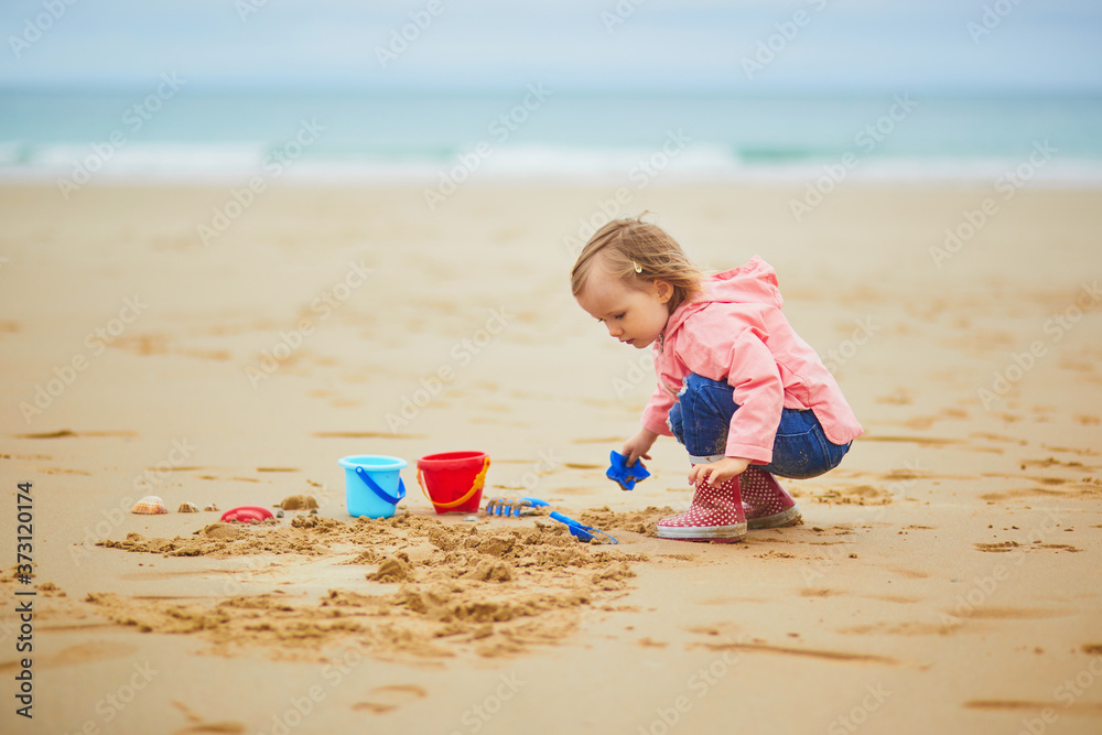 Adorable toddler girl on the sand beach at Atlantic coast of Brittany, France Adorable toddler girl on the sand beach at Atlantic coast of Brittany, France