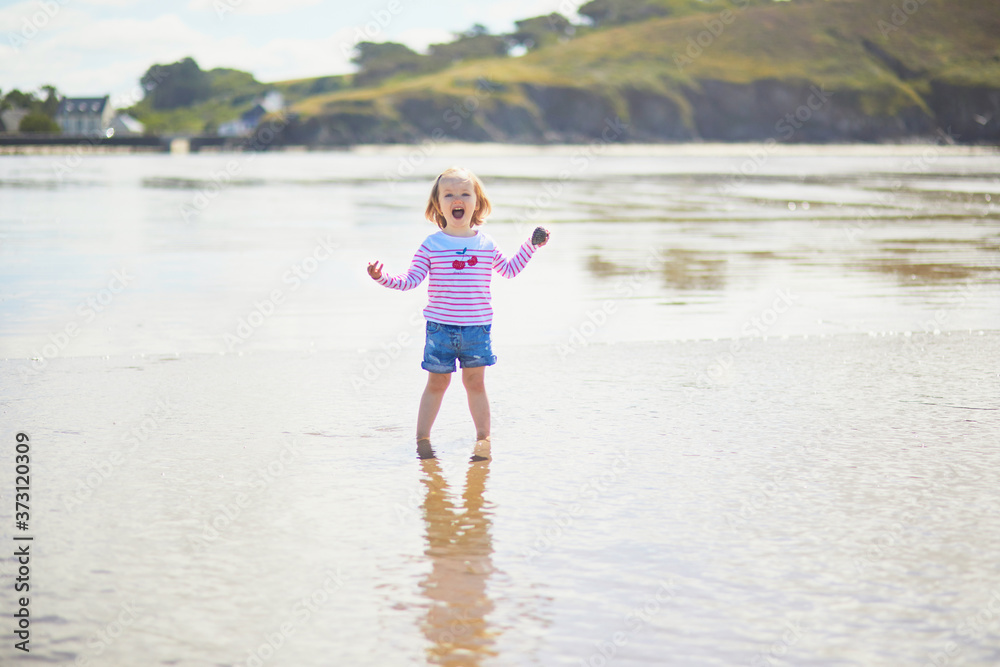 Adorable toddler girl on the sand beach at Atlantic coast of Brittany, France