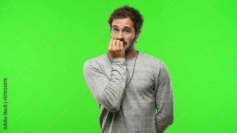 young man on chroma green screen biting nails, nervous and very anxious young man on chroma green screen biting nails, nervous and very anxious