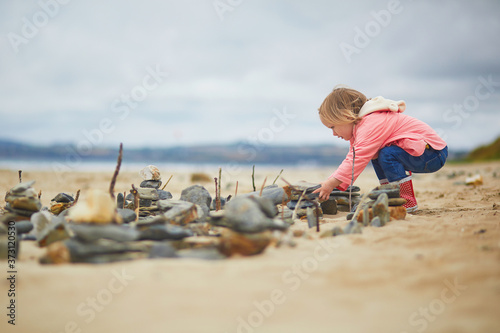 Billede på lærred Adorable toddler girl on the sand beach at Atlantic coast of Brittany, France