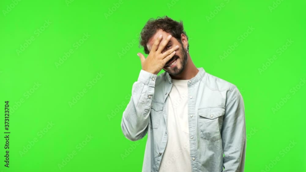 young man on chroma green screen embarrassed but laughing young man on chroma green screen embarrassed but laughing