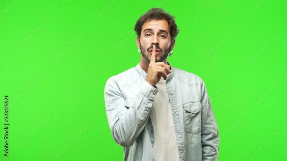 young man on chroma green screen keeping a secret or asking for silence young man on chroma green screen keeping a secret or asking for silence