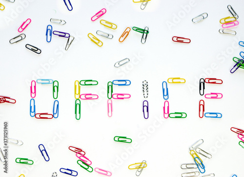 Made up of multi-colored paper clips the word office on a white background surrounded by other colored paper clips