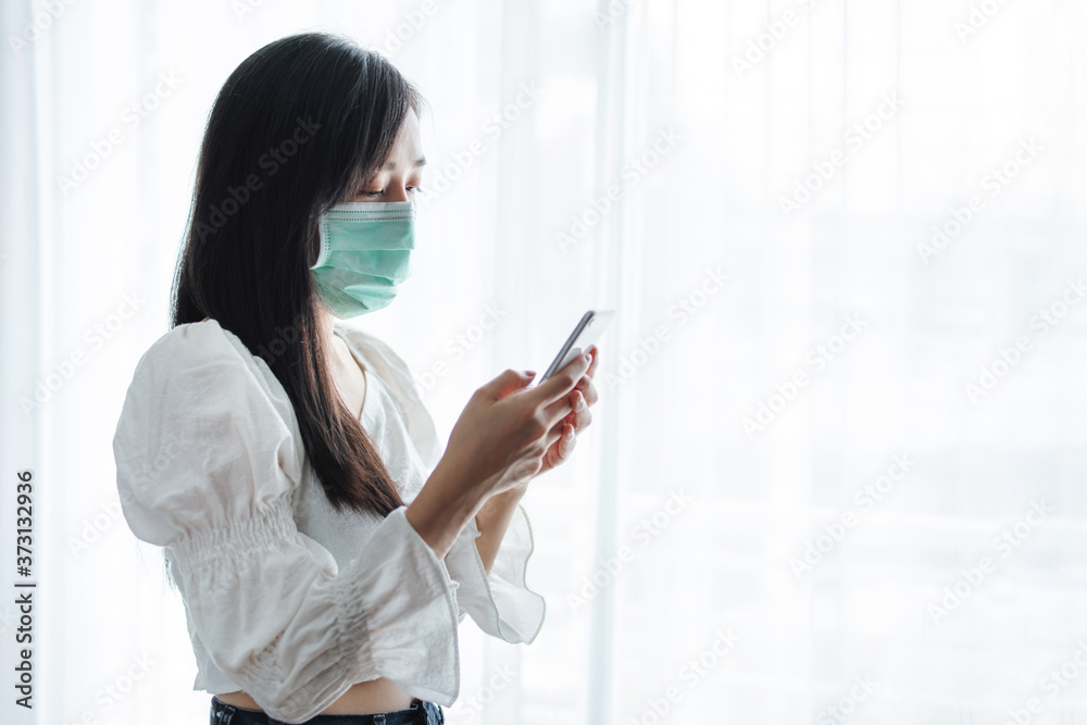Asian woman wearing protective face mask, and using mobile smartphone Asian woman wearing protective face mask, and using mobile smartphone
