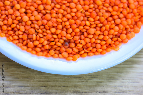 Red lentils in a round white plate: ingredients for a healthy diet natural meal